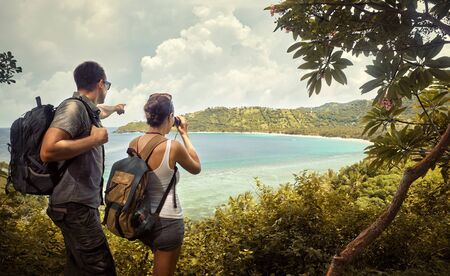 Tourist couple  with backpacks enjoying views coast island Lombok. Indonesia.Traveling along mountains and coast, freedom and active lifestyle concept.の写真素材