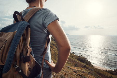 Hipster woman traveler with backpack enjoying sunset on the coast.Coast and sea landscape, travel to Asia, happiness emotion, summer holiday conceptの写真素材