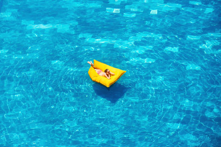 Top view of woman relaxing in outdoor pool, tropical summer vacation holiday concept