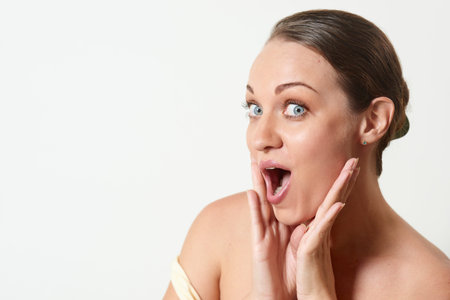 Surprised happy young woman over white background. Expressive facial expressions, positive emotions.の写真素材
