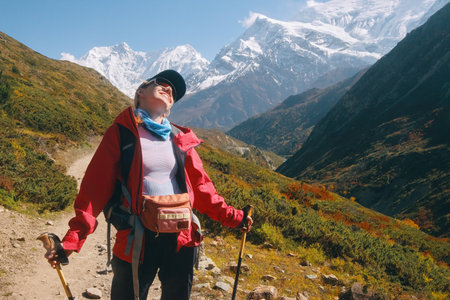 Happy young woman with trekking poles laughing while resting in Himalaya mountains, Nepal. Travel, lifestyle concept for outdoor sports.の写真素材