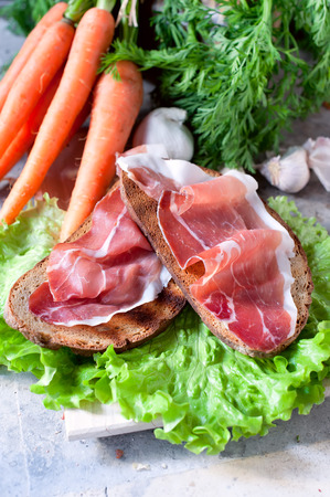 Rustic snack Prosciutto over a toasted piece of wheat bread and saladの写真素材