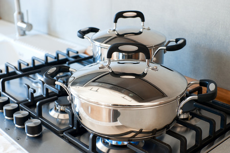 Two saucepans stainless steel on gas stoveの写真素材