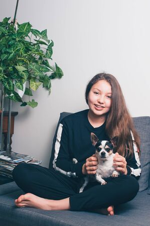 Happy teenage girl with a puppy.  Girl have fun with her dog in house. Dog owner having fun with pet at home. Concept human and pets. Friendship between human and dog. Teenager with Dog. Brace face.の写真素材
