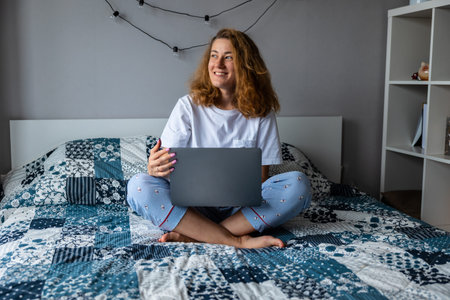 Young beautiful woman on the sofa with a laptop, looking out the window, smiling