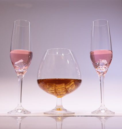 pink champagne and cognac glass with ice glasses up. White backgroundの写真素材