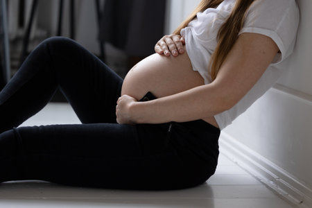 Close-up belly pregnant girl white top fingers hands folded heart stomach concept happy motherhood preparation for birthの写真素材