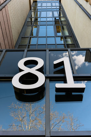 Large numbers on the facade of the house. Glass facade of the building.