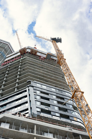 A view from below of a skyscraper under construction. Glazing of the facade of the building....