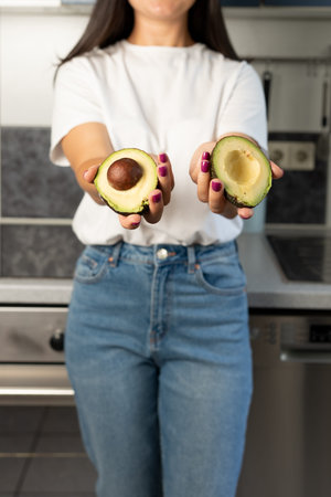 Woman holds a green cut avocado in her hands. Avocado close-up. Healthy food, raw food diet....