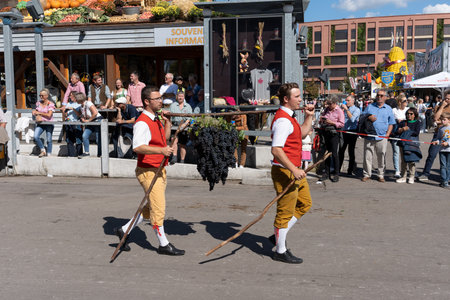 Stuttgart, Germany, 24 September 2023. Beer Festival in Stuttgart. Two guys are carrying a huge bunch of grapes.のeditorial素材
