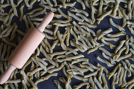 The composition is ideal for topics related to gastronomy, cooking and traditional ItalOn the pasta there is a wooden rolling pin, symbolizing the process of making homemade pasta.の写真素材