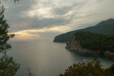 rocky shore and the sunset in the sea cliffs, overlooking the blue sea and the green of the pine needles of the pine trees, nature of Montenegroの写真素材