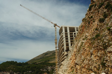 the construction of the hotel in the rock by the sea, beach,stones,building construction craneの写真素材