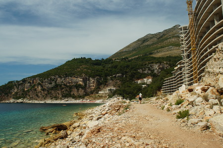 the construction of the hotel in the rock by the sea, beach,stones,building construction craneの写真素材
