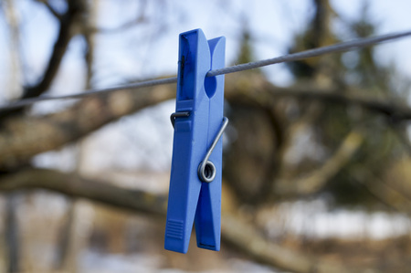 mount to hang linen and Old clothespins weigh on a twisted rope on the background of trees and blue skyの写真素材