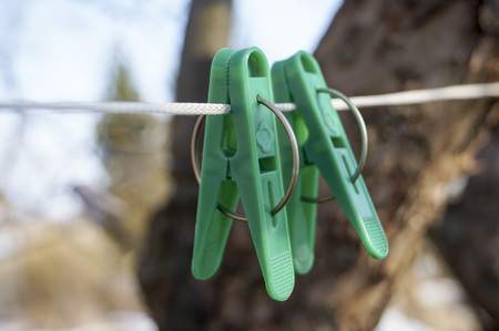mount to hang linen and Old clothespins weigh on a twisted rope on the background of trees and blue skyの写真素材