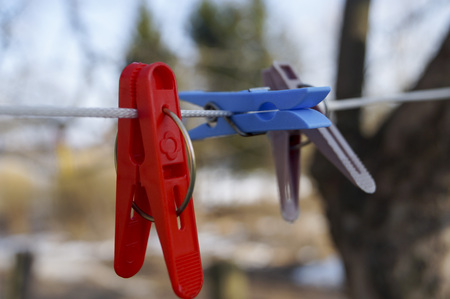 mount to hang linen and Old clothespins weigh on a twisted rope on the background of trees and blue skyの写真素材