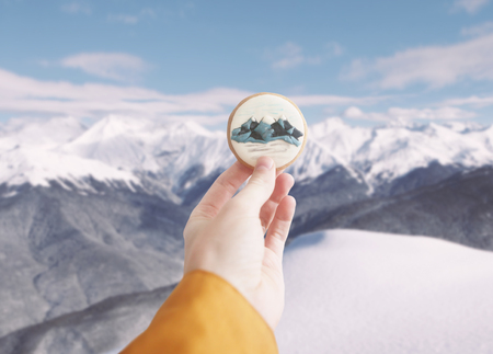 Holding ginger cookie with mountains print.の写真素材