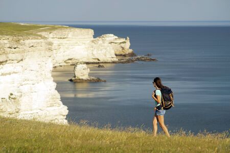 Young woman with backpack hiking at seaside.の写真素材