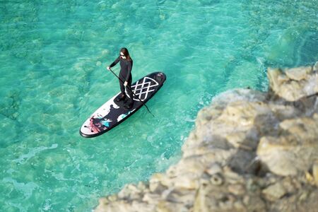 Woman Paddling on SUP board in a blue sea.  の写真素材