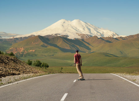 Man Riding on skateboard on Road to Elbrus, Highest Mount in Europe.