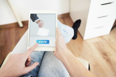 Man Voting Online Sitting at Home Using Digital Tablet.の写真素材