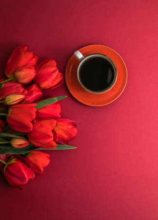 Bouquet of red tulips and coffee cup arrangement with a lot of copy space for text. Spring mood concept. Greeting card for Birthday, Woman, Mother's Day, Wedding, Valentines day.の写真素材