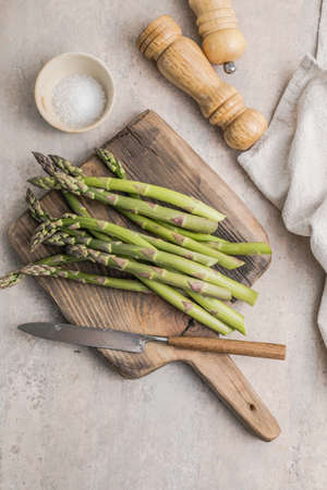 Asparagus cooking concept, top down view on a cutting board with fresh bunch of asparagus, spring healthy cooking ideaの写真素材