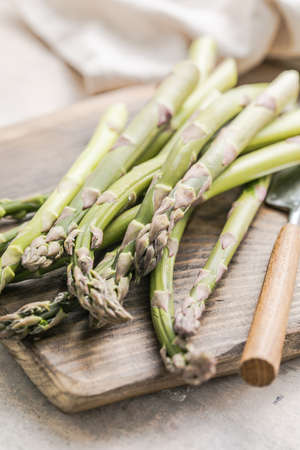 Asparagus cooking concept, top down view on a cutting board with fresh bunch of asparagus, spring healthy cooking ideaの写真素材