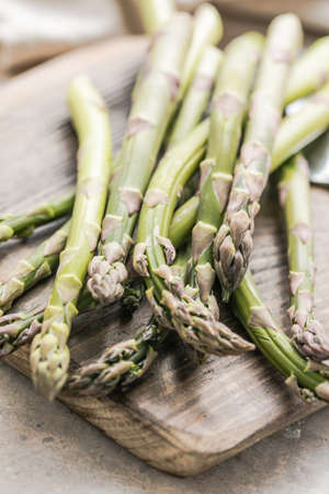 Asparagus cooking concept, top down view on a cutting board with fresh bunch of asparagus, spring healthy cooking ideaの写真素材