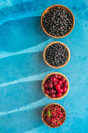 Fresh organic summer berries mix on blue concrete background. Blueberries, red black currant and cherries. Top view. Concept of summer food. Flat lay, copy spaceの写真素材