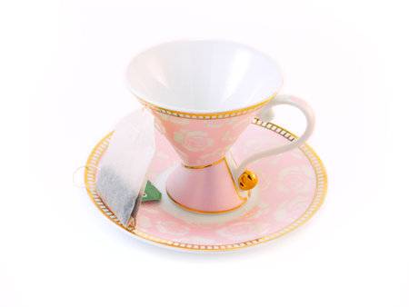 Pink tea cup on a saucer and a tea bagの写真素材