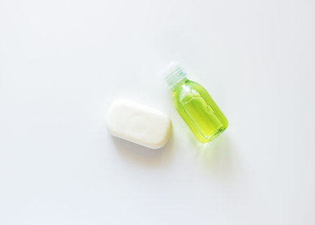 White transparent bottle with yellow-green liquid and white soap on a white background