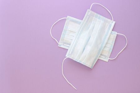 two used white torn masks on a purple pink backgroundの写真素材