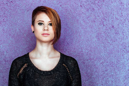 Beautiful girl in black shirt on a purple background with short haircutの写真素材