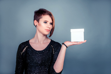Cute young girl holding box on a hand on grey backgroundの写真素材