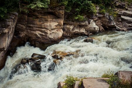 Water flows swiftly over a stream's rocky bottom in carpathian mountainsの写真素材
