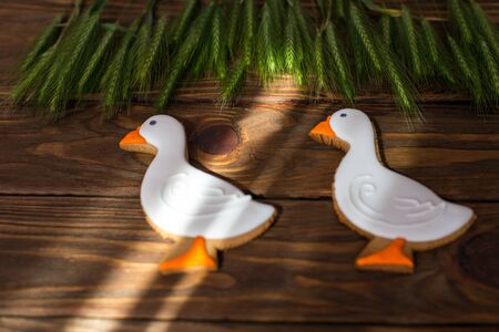 Gingerbread cookies shaped duck with ear of wheat on a brown wooden backgroundの写真素材