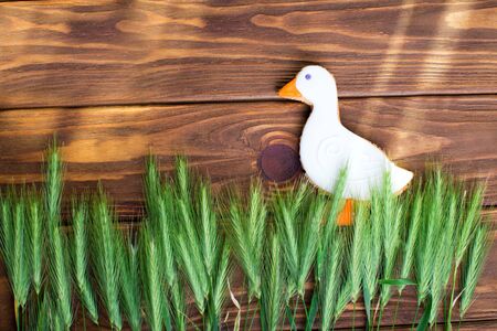 Gingerbread cookies shaped duck with ear of wheat on a brown wooden background. Shallow depth of field.の写真素材