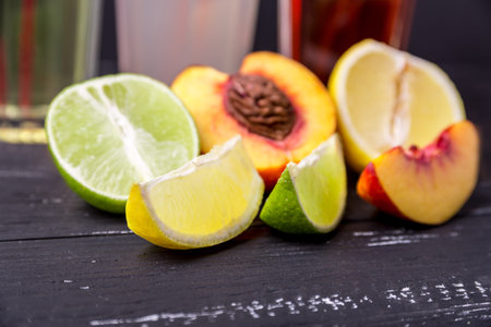 Halves and slices of lemon. peach and lime on a dark wooden textured background and soft drinks....