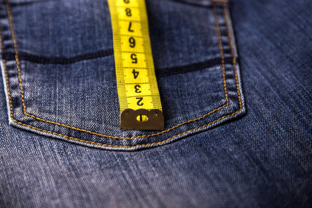 Close view on measure tape on a back pocket of blue denim. Background and texture.の写真素材