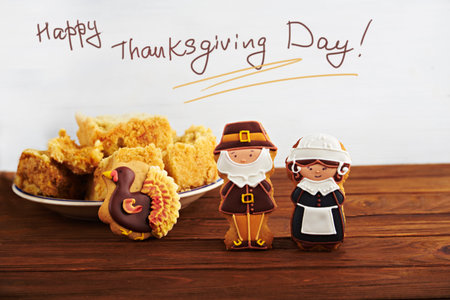 Happy Thanksgiving card. Close view at figures of gingerbread pilgrims with Thanksgiving pumpkin pie on a back on a wooden background. With the sign.の写真素材