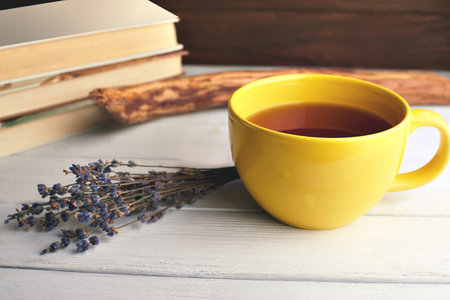 Still life with big yellow cup of tea, lavender and books on a wooden background. Soft vintage colors.の写真素材