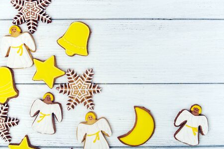 Background of christmas white and yellow gingerbread cookies with christmas figures snowflakes, angels and stars on white wooden background. Top view.  With copy spaceの写真素材