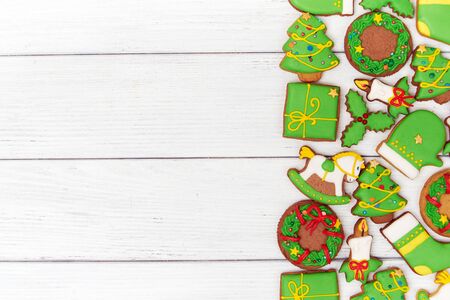Background of christmas green gingerbread cookies with christmas figures on white wooden background. Top view.  With copy space on the leftの写真素材