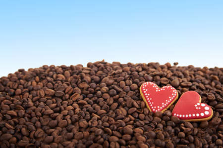 close view at gingerbread heart shaped cookies. Scattered coffee beans on blue background. Copy spaceの写真素材