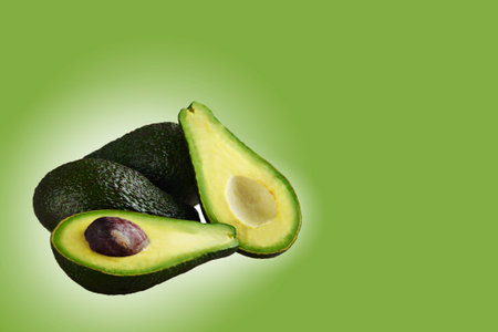 Avocado cut into halves isolated on a green background.