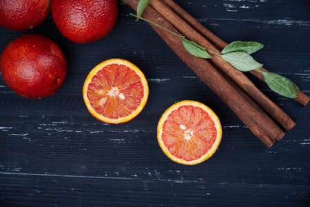 Fresh bloody oranges with cinnamon sticks on a rustic wooden backgroundの写真素材