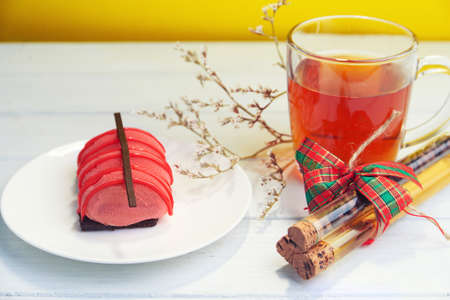 Mini cake on a plate with strawberry cream, dark chocolate and creamy mousse and cup of tea with coffee beansの写真素材
